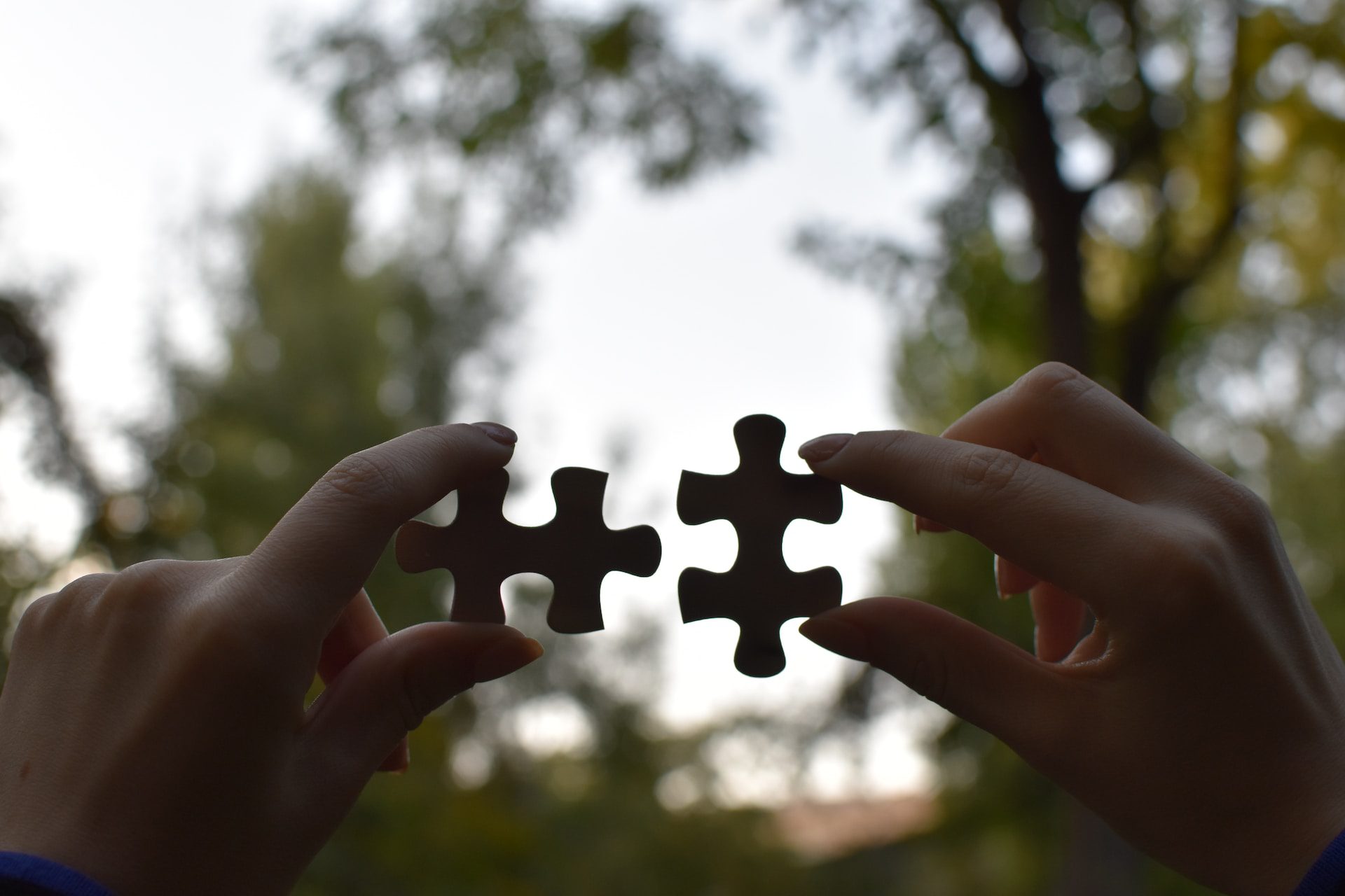 Hands fitting together puzzle pieces