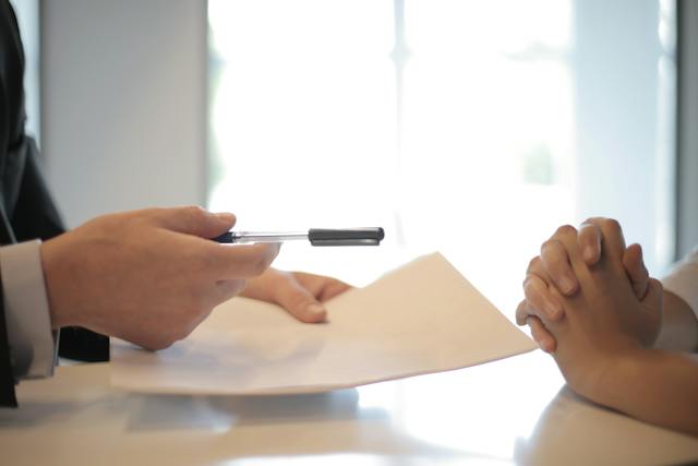 Person Giving Loan Servicing Printed Documents and Pen to Client